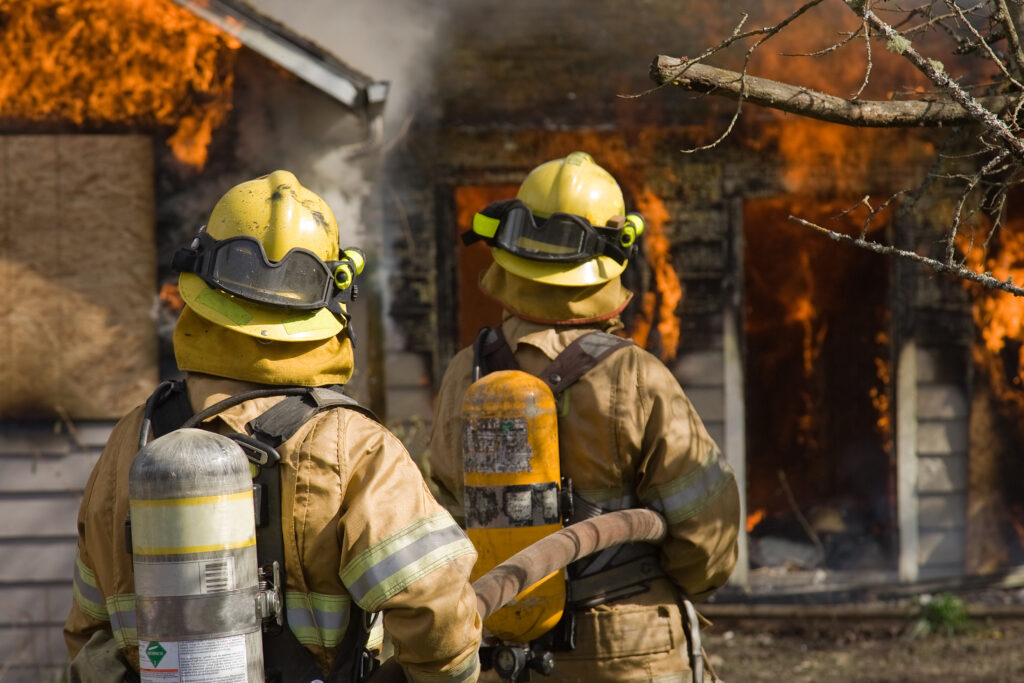 Fire fighters standing by large fire