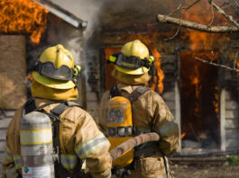 Fire fighters standing by large fire