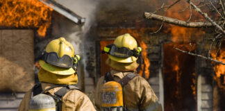 Fire fighters standing by large fire