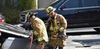 Emergency respondents take emergency precautions to remove car accident victim from crashed vehicle