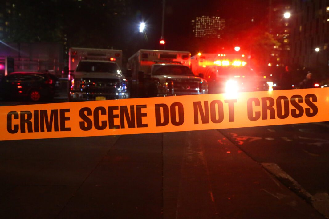 Emergency respondents at scene of car accident surrounded by police tape