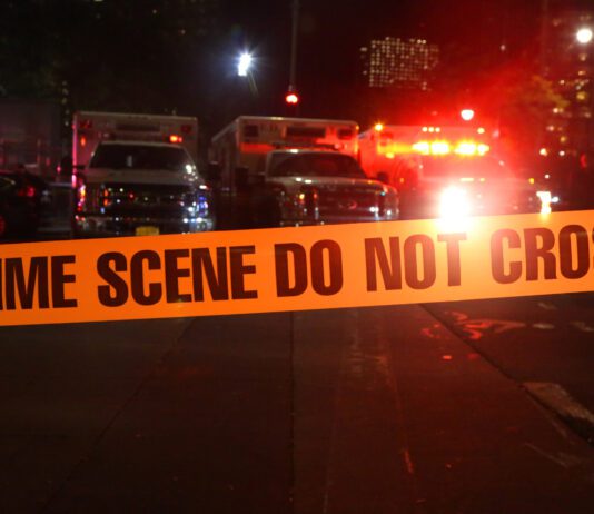 Emergency respondents at scene of car accident surrounded by police tape