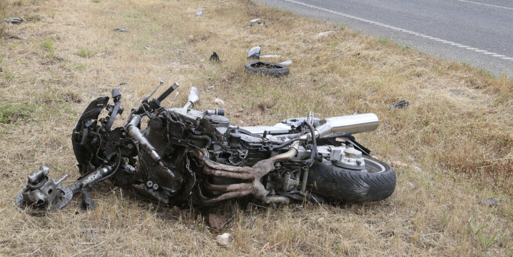 Crashed motorcycle scattered on side of road
