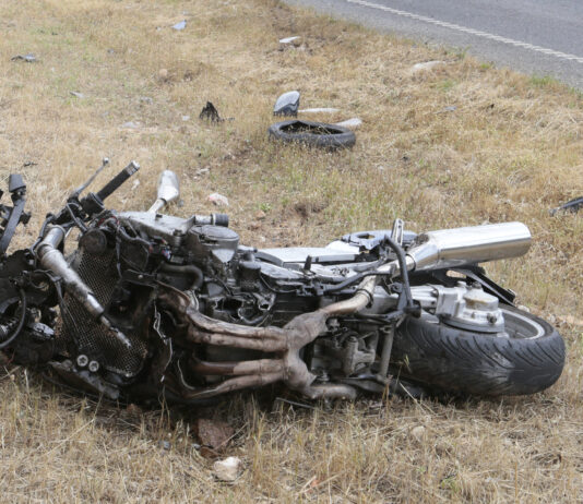 Crashed motorcycle scattered on side of road