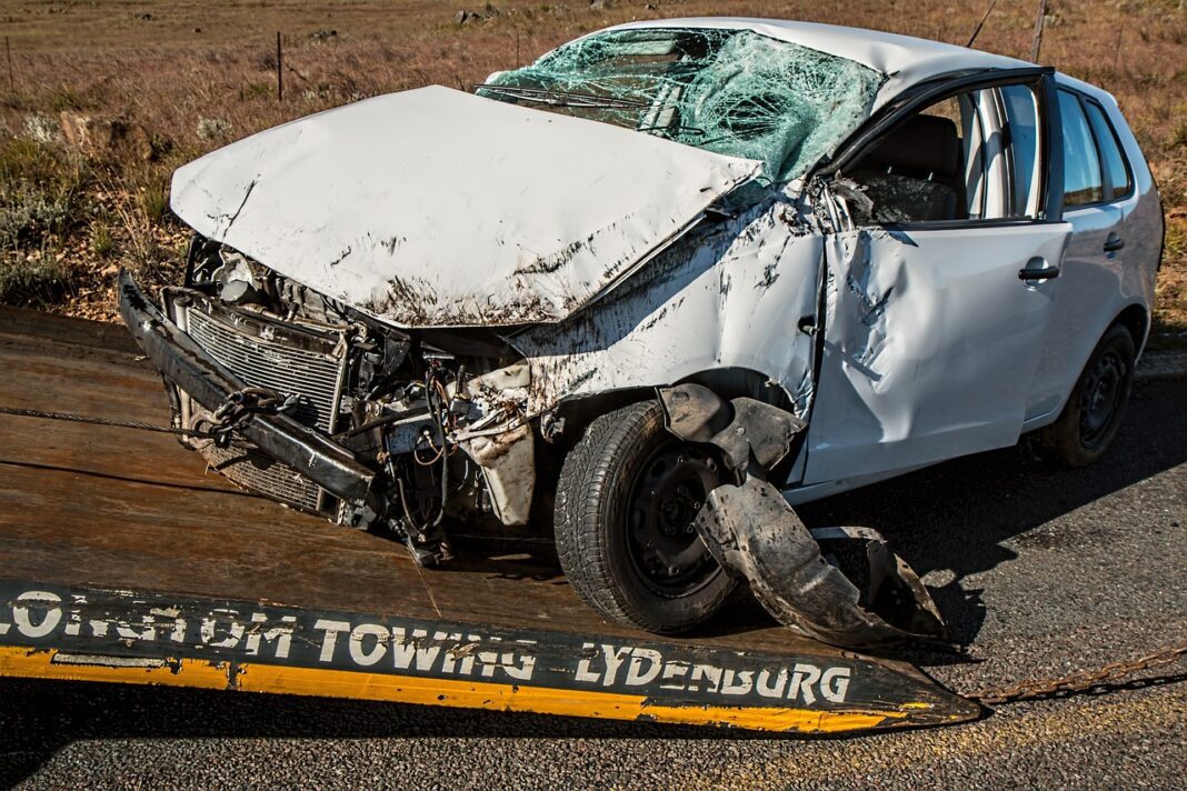 White car severely wrecked following car accident displayed on a tow truck