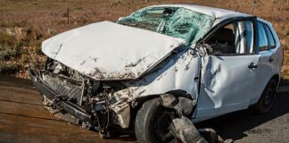 White car severely wrecked following car accident displayed on a tow truck