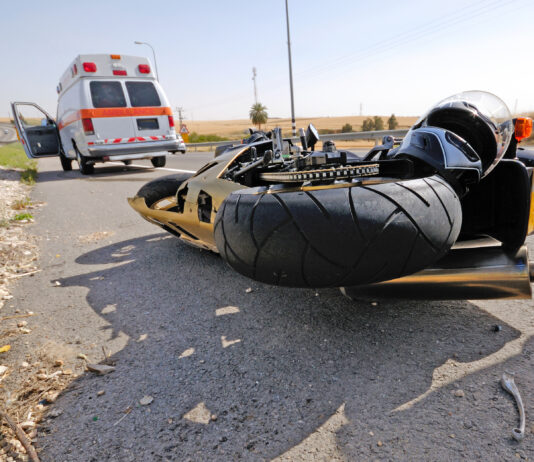 Emergency respondents arrive to scene of accident where a crashed motorcycle is on the ground