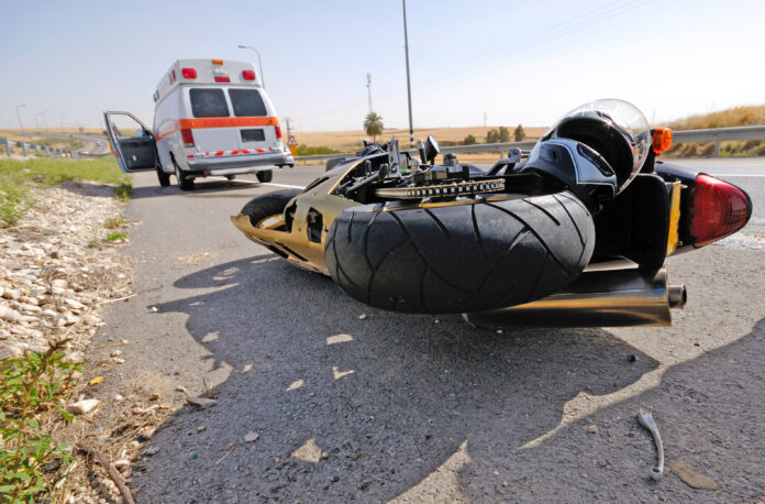 Emergency respondents arrive to scene of accident where a crashed motorcycle is on the ground