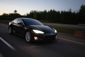 Black Tesla being driven on highway 