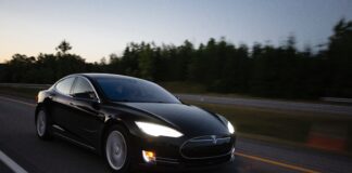 Black Tesla being driven on highway