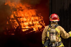 firefighter attempts to put out large structural fire 