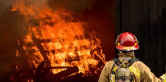 firefighter attempts to put out large structural fire