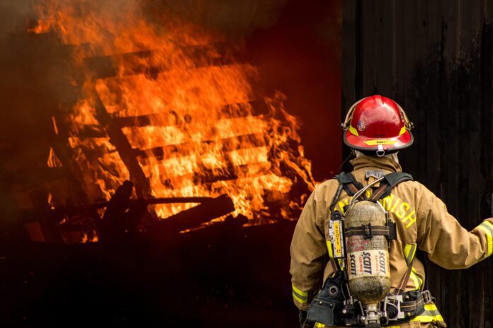 firefighter attempts to put out large structural fire