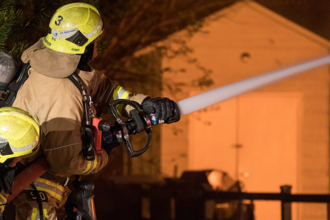 firefighter works to extinguish flames of house fire