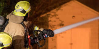 firefighter works to extinguish flames of house fire