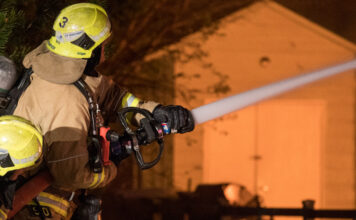 Oceanside Housefire Harms 1, Displaces 13 firefighter works to extinguish flames of house fire