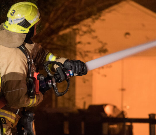 firefighter works to extinguish flames of house fire